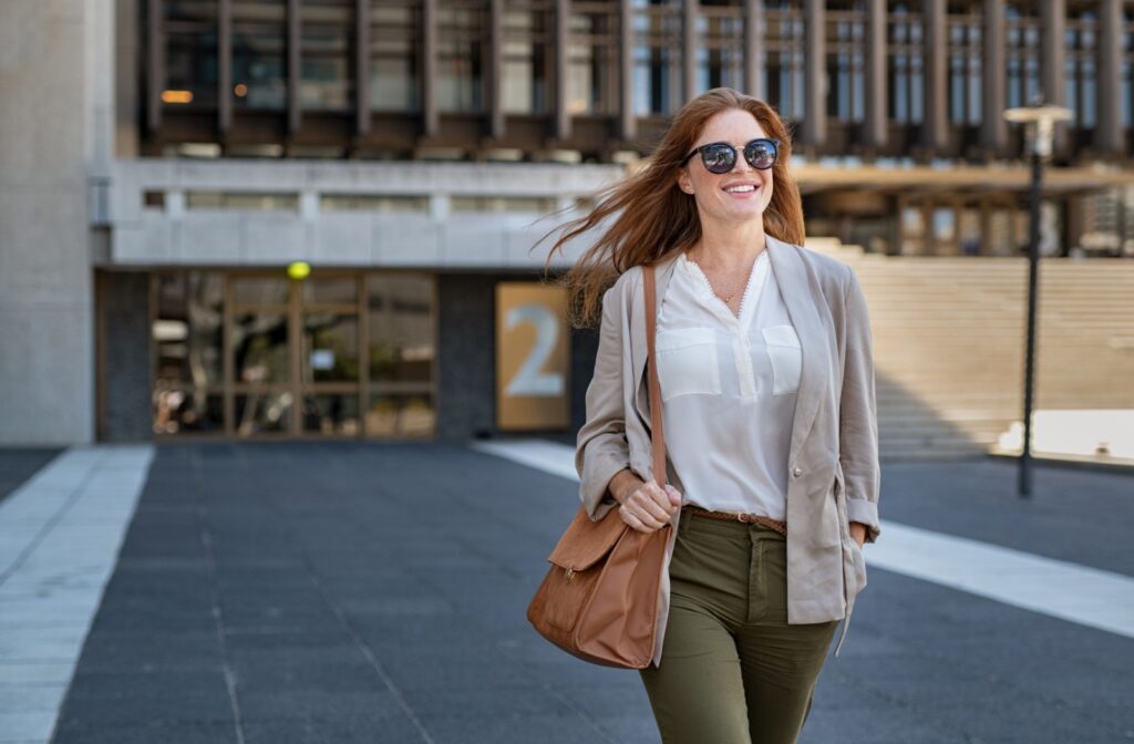 A woman wearing sunglasses leaving a building to protect her blue eyes that are sensitive to light