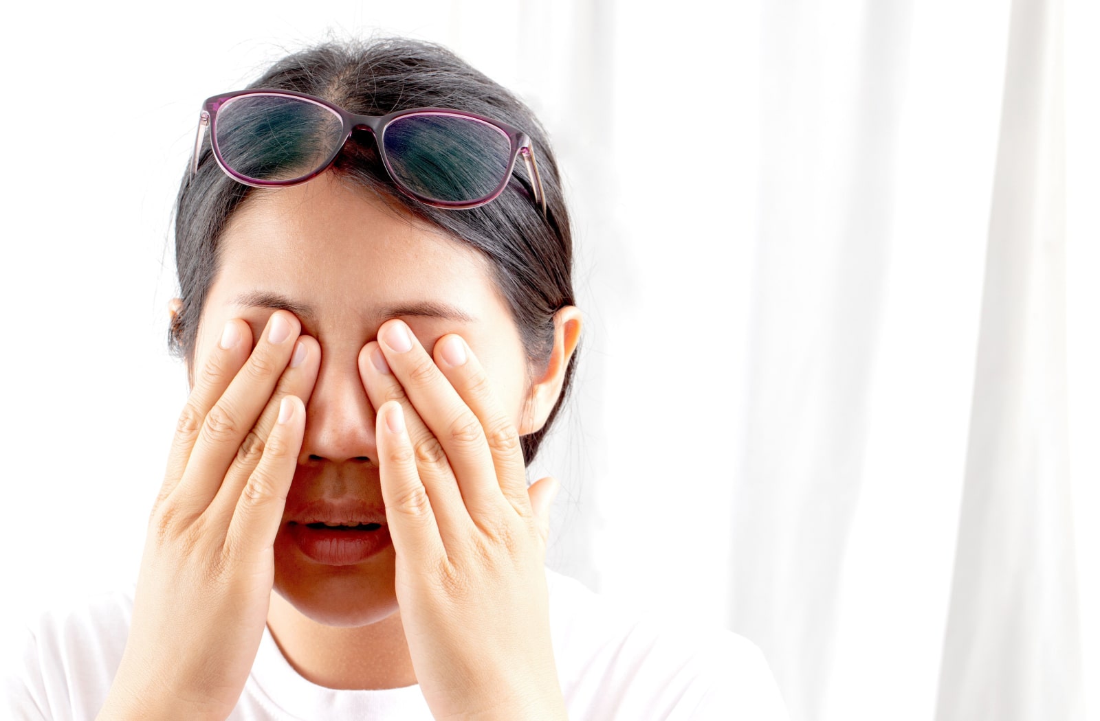 A woman massaging her eyes, suffering from blurry, poor vision