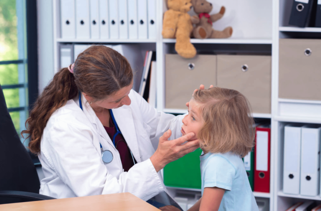A woman optometrist is carefully examining the eye of a young girl, gently holding the eyelid to keep the eye open.