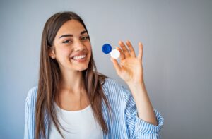 A young woman proudly holds up her new contact lens