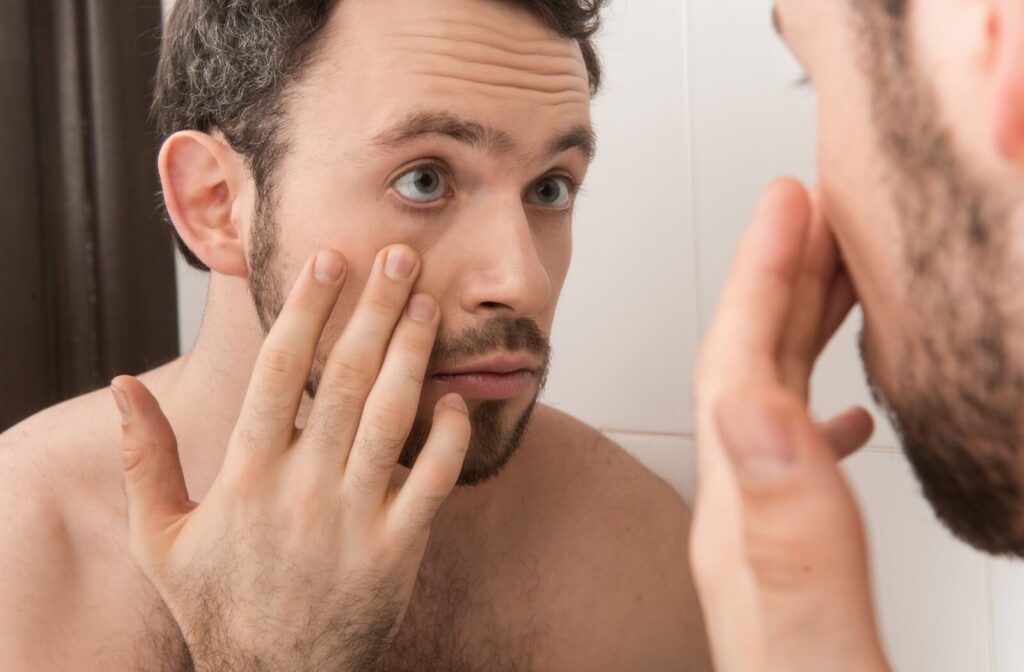 A person examines their eye in the mirror, looking for a missing contact lens.