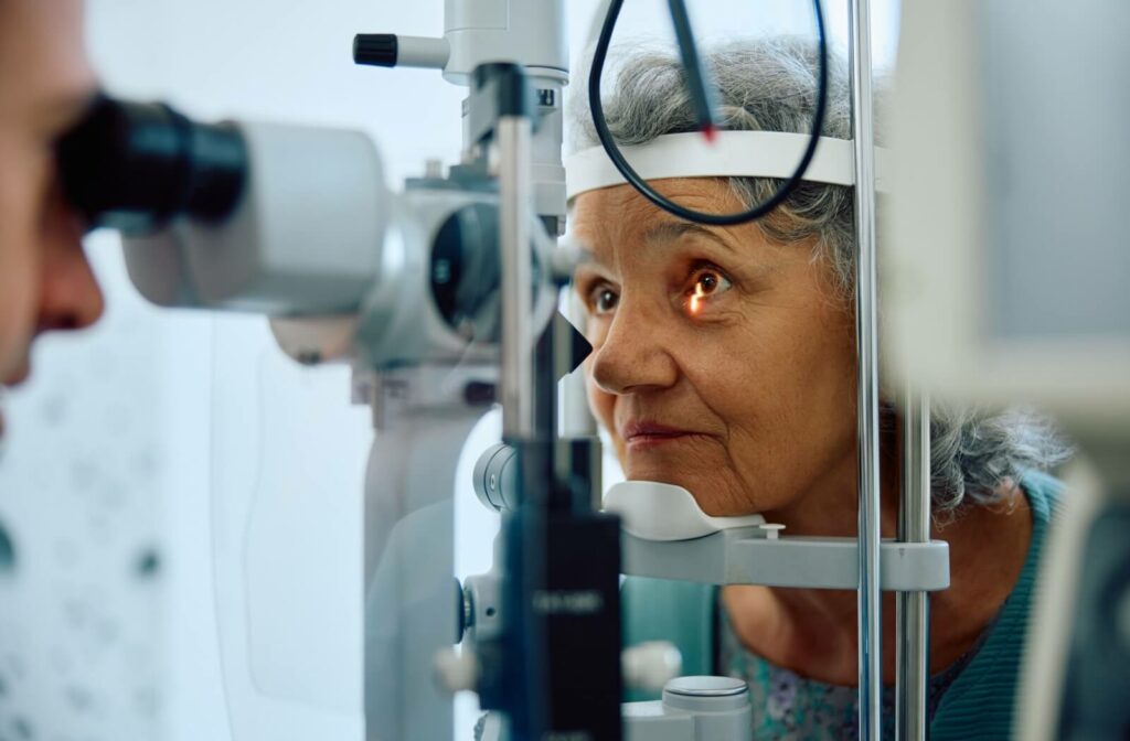 A close-up image of an older adult during a slit-lamp eye exam with their optometrist.